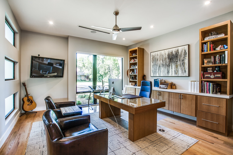 Diseño de despacho contemporáneo con paredes grises, suelo de madera en tonos medios, escritorio independiente y suelo marrón