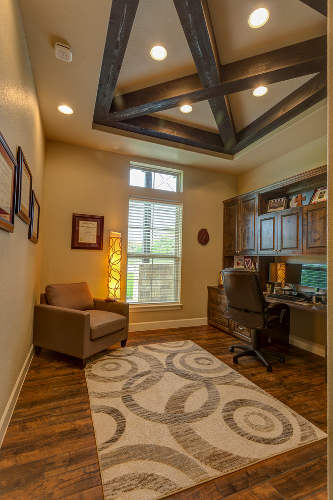 Mittelgroßes Rustikales Arbeitszimmer ohne Kamin mit beiger Wandfarbe, dunklem Holzboden, Einbau-Schreibtisch und braunem Boden in Austin