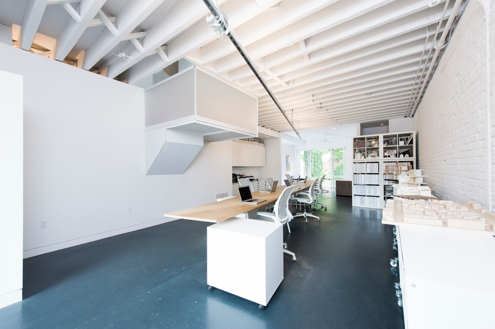 На фото: домашняя мастерская в стиле лофт с белыми стенами, бетонным полом и отдельно стоящим рабочим столом