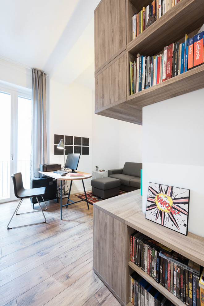 Diseño de estudio minimalista con paredes blancas, suelo de madera clara y escritorio independiente