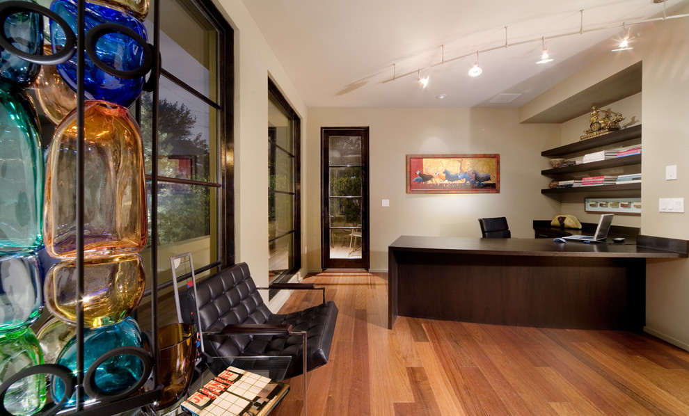 Cette photo montre un bureau tendance avec un mur beige, un sol en bois brun et un bureau intégré.