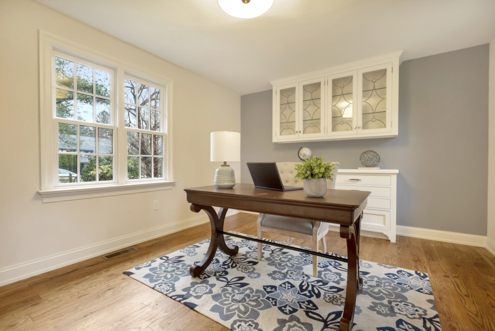 Immagine di uno studio minimal di medie dimensioni con pareti blu, pavimento in legno massello medio, scrivania autoportante e pavimento marrone