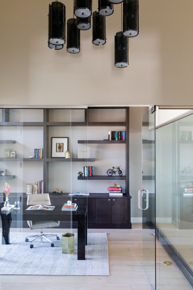 Foto de despacho contemporáneo de tamaño medio sin chimenea con paredes beige, suelo de madera clara y escritorio independiente