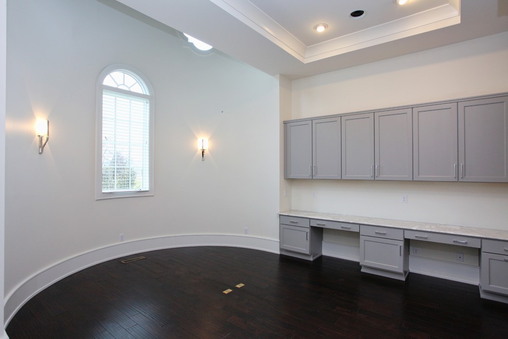 Ejemplo de despacho contemporáneo extra grande con paredes blancas, suelo de madera oscura, escritorio empotrado y suelo marrón