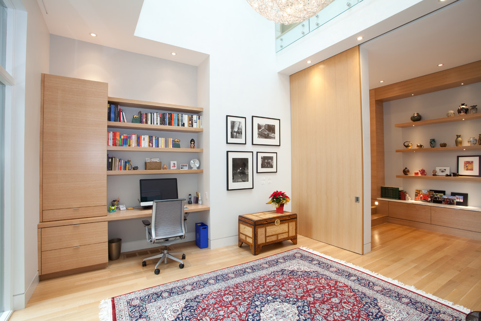 Cette image montre un grand bureau design avec un bureau intégré, un mur blanc, parquet clair et aucune cheminée.