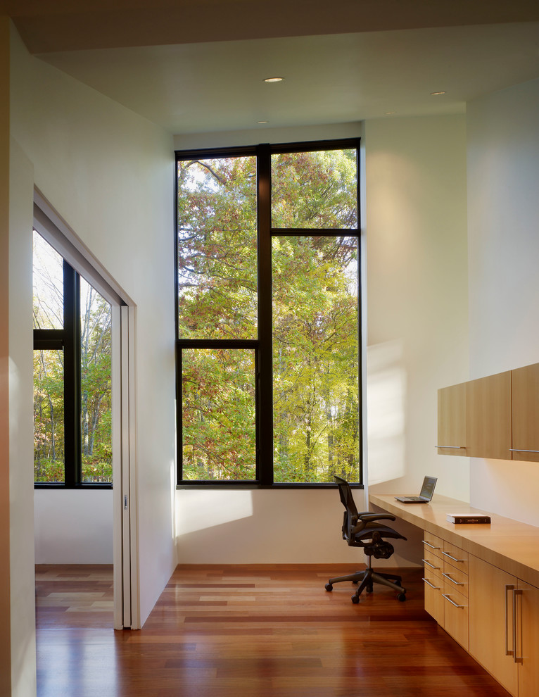 На фото: кабинет в современном стиле с белыми стенами и встроенным рабочим столом с