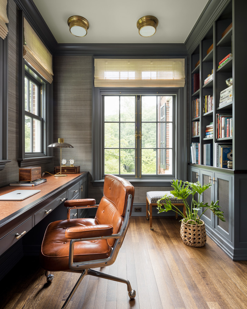 ニューヨークにあるトラディショナルスタイルのおしゃれなホームオフィス・書斎 (グレーの壁、濃色無垢フローリング、造り付け机、茶色い床) の写真