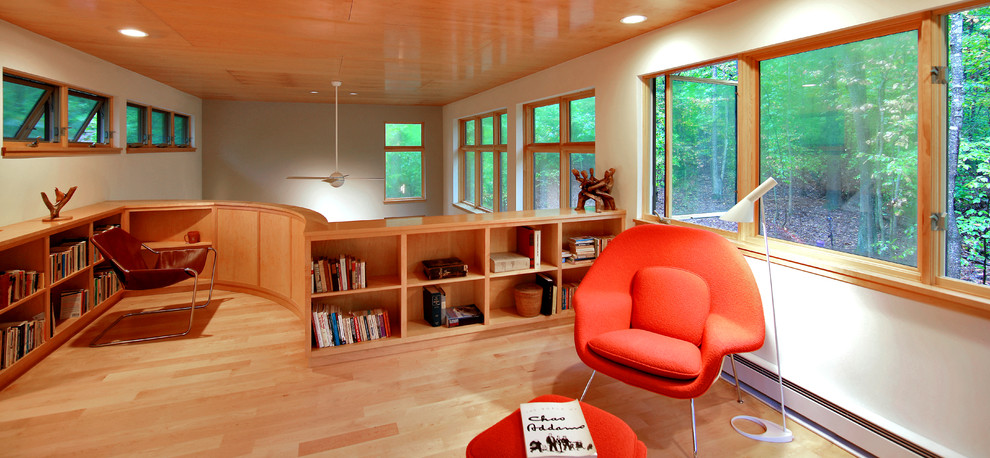 Modern inredning av ett mellanstort hemmabibliotek, med vita väggar och ljust trägolv