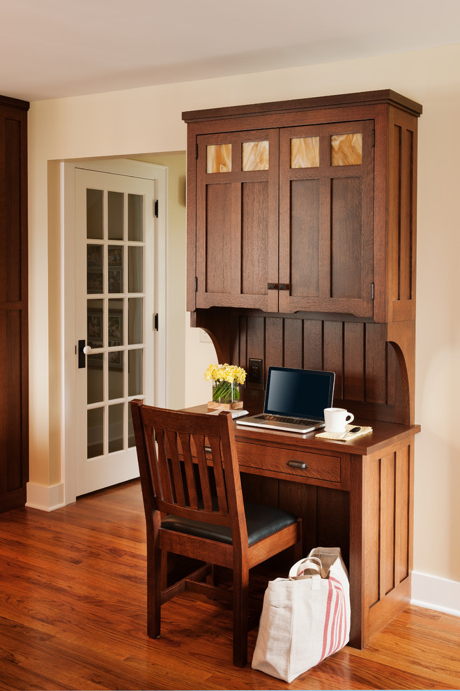 Réalisation d'un bureau craftsman avec un mur beige et un sol en bois brun.