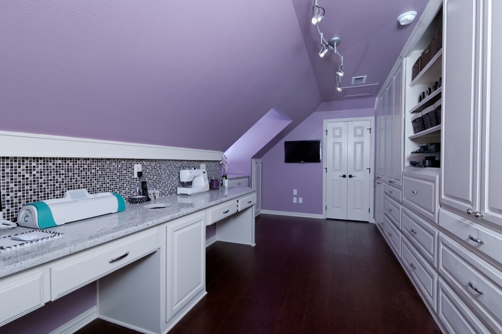 Mid-sized elegant built-in desk dark wood floor and brown floor craft room photo in Dallas with purple walls and no fireplace