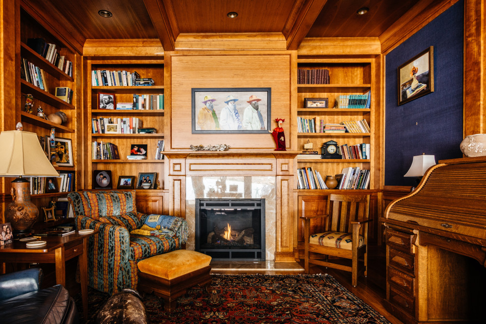 ナッシュビルにある広いトラディショナルスタイルのおしゃれな書斎 (青い壁、無垢フローリング、標準型暖炉、石材の暖炉まわり、茶色い床、自立型机、板張り天井、羽目板の壁、壁紙) の写真
