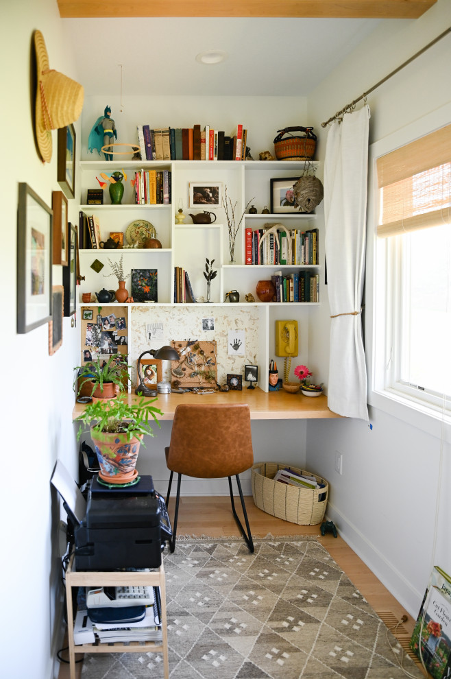 Foto på ett eklektiskt arbetsrum, med vita väggar, mellanmörkt trägolv, ett inbyggt skrivbord och brunt golv