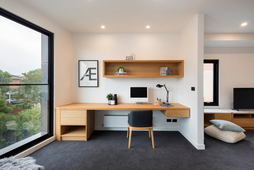 Inredning av ett modernt arbetsrum, med vita väggar, heltäckningsmatta, ett inbyggt skrivbord och svart golv