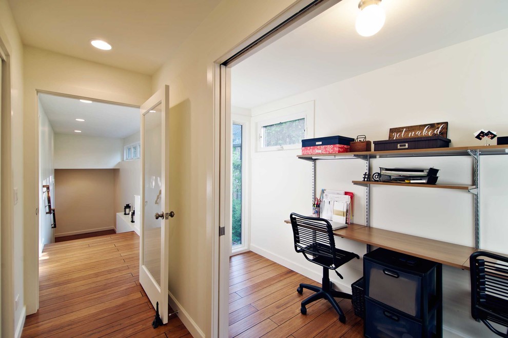 Foto de despacho clásico renovado de tamaño medio sin chimenea con paredes beige, suelo de bambú y escritorio empotrado