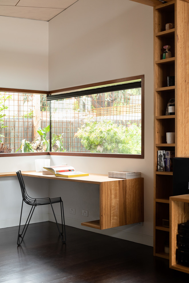 Idée de décoration pour un bureau design avec un mur blanc, parquet foncé, un bureau intégré et un sol marron.