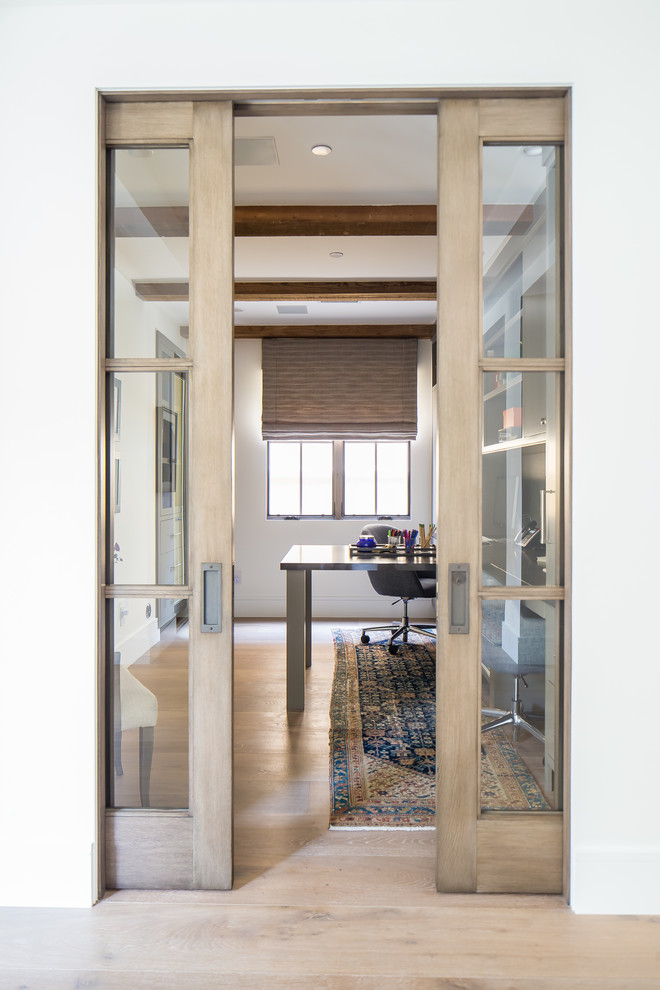 Immagine di un grande studio mediterraneo con pareti bianche, pavimento in legno massello medio, scrivania incassata e pavimento marrone