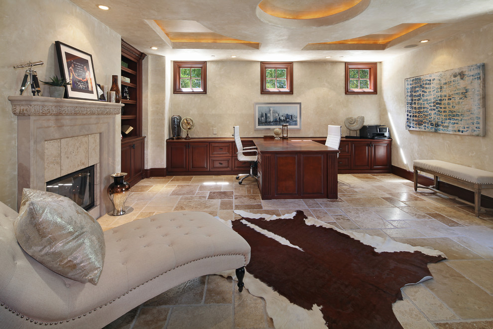 Study room - large transitional built-in desk limestone floor and beige floor study room idea in Orange County with beige walls, a standard fireplace and a tile fireplace