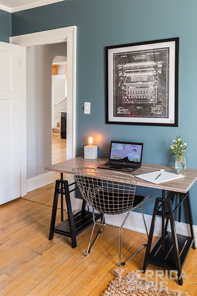 Mittelgroßes Industrial Arbeitszimmer mit Arbeitsplatz, blauer Wandfarbe, hellem Holzboden, freistehendem Schreibtisch und braunem Boden