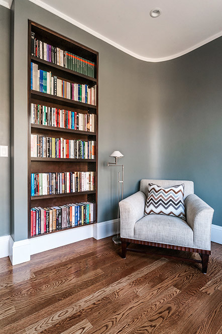 Пример оригинального дизайна: домашняя библиотека среднего размера в стиле неоклассика (современная классика) с серыми стенами, паркетным полом среднего тона, встроенным рабочим столом и коричневым полом без камина