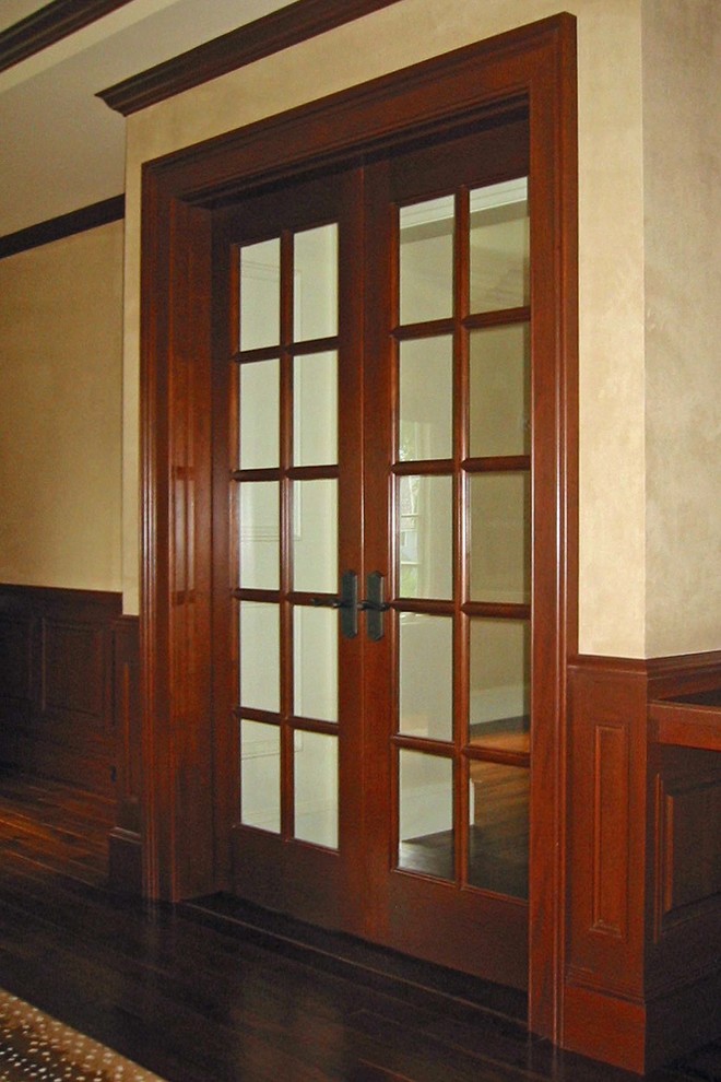Diseño de despacho tradicional de tamaño medio con biblioteca, paredes beige, suelo de madera oscura, escritorio empotrado y suelo marrón
