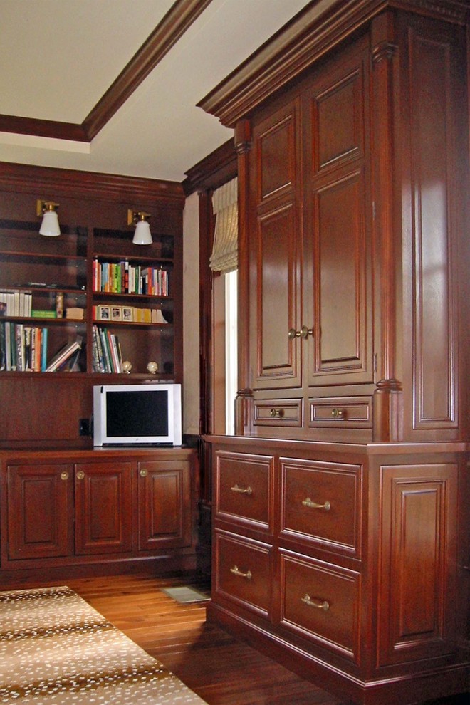 Diseño de despacho clásico de tamaño medio con biblioteca, paredes beige, suelo de madera oscura, escritorio empotrado y suelo marrón