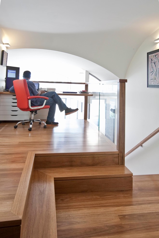 Exemple d'un bureau tendance de taille moyenne avec une bibliothèque ou un coin lecture, un mur blanc, parquet clair, un bureau intégré et un sol marron.