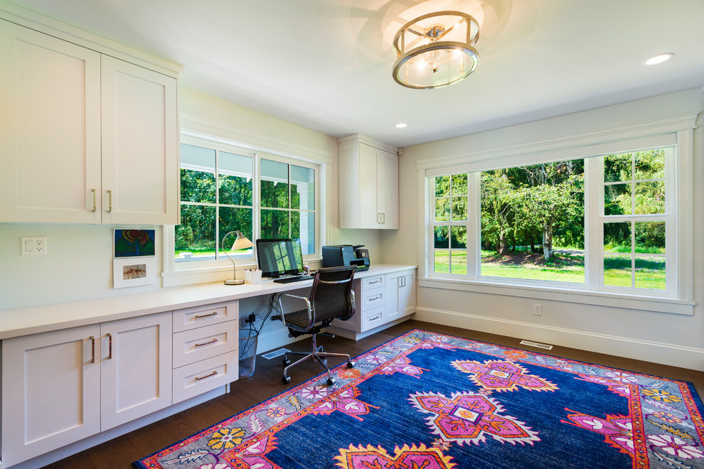 Foto de despacho clásico renovado de tamaño medio con paredes blancas, suelo de madera en tonos medios, escritorio empotrado y suelo marrón