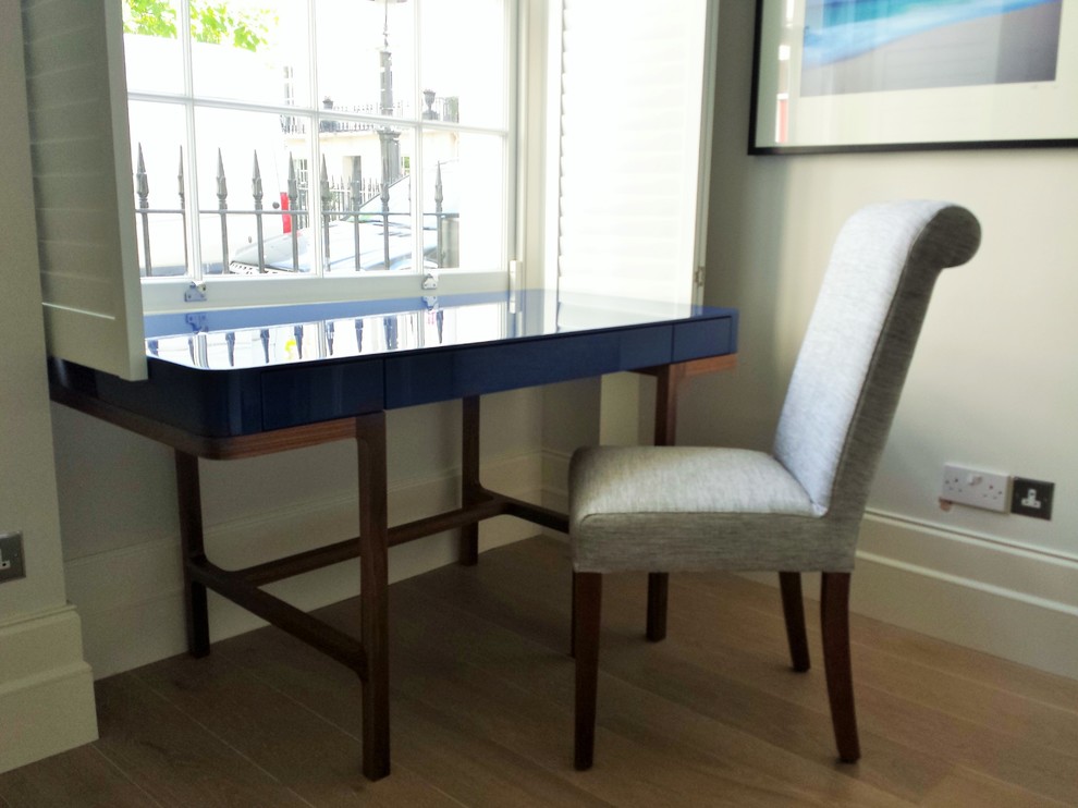 This is an example of a small modern study in London with light hardwood flooring and a freestanding desk.