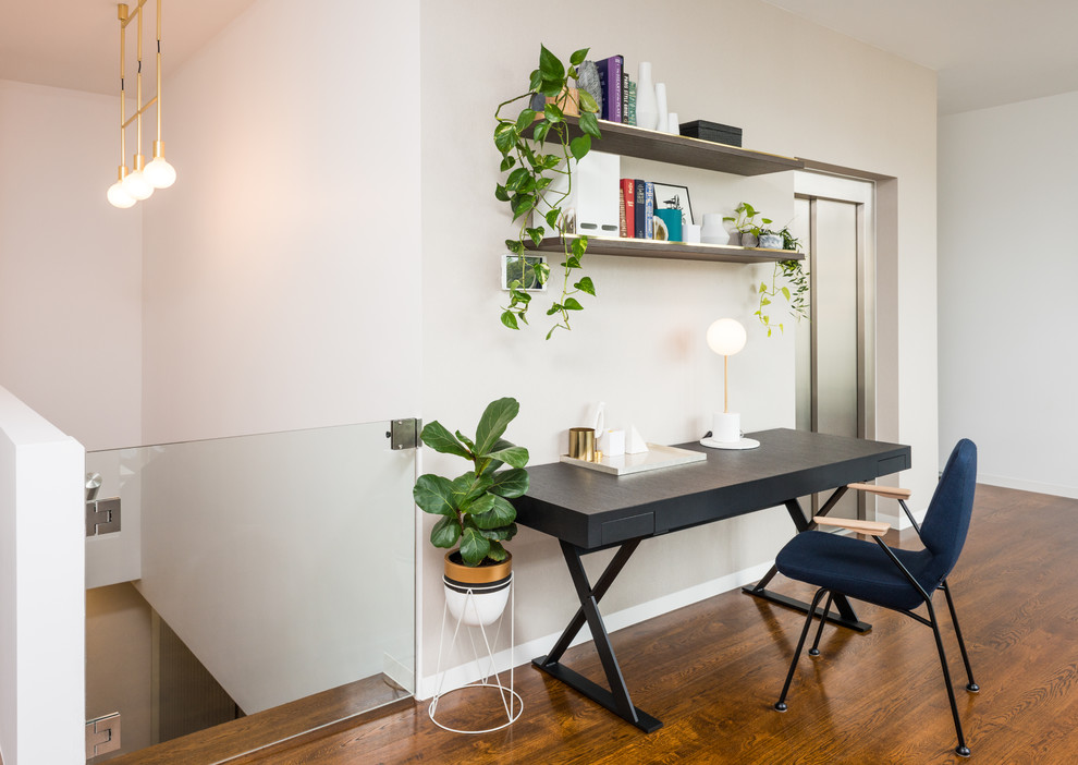 Idéer för ett modernt arbetsrum, med vita väggar, mörkt trägolv, ett fristående skrivbord och brunt golv