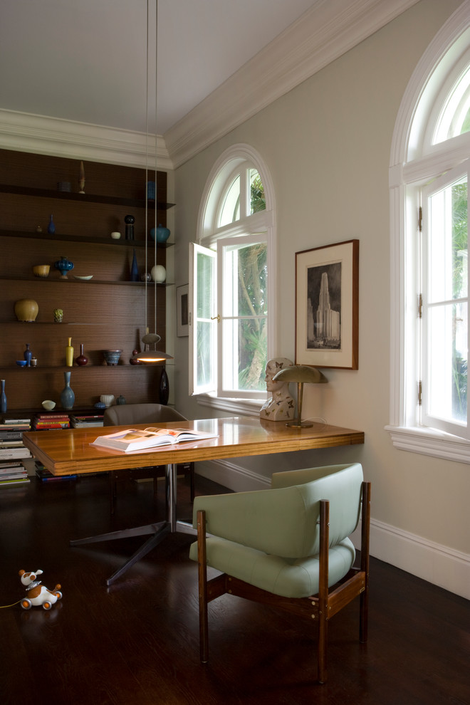 Diseño de despacho contemporáneo con paredes beige, suelo de madera oscura y escritorio independiente