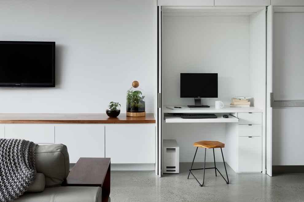Mittelgroßes Modernes Arbeitszimmer mit weißer Wandfarbe, Betonboden, Einbau-Schreibtisch und grauem Boden in Melbourne
