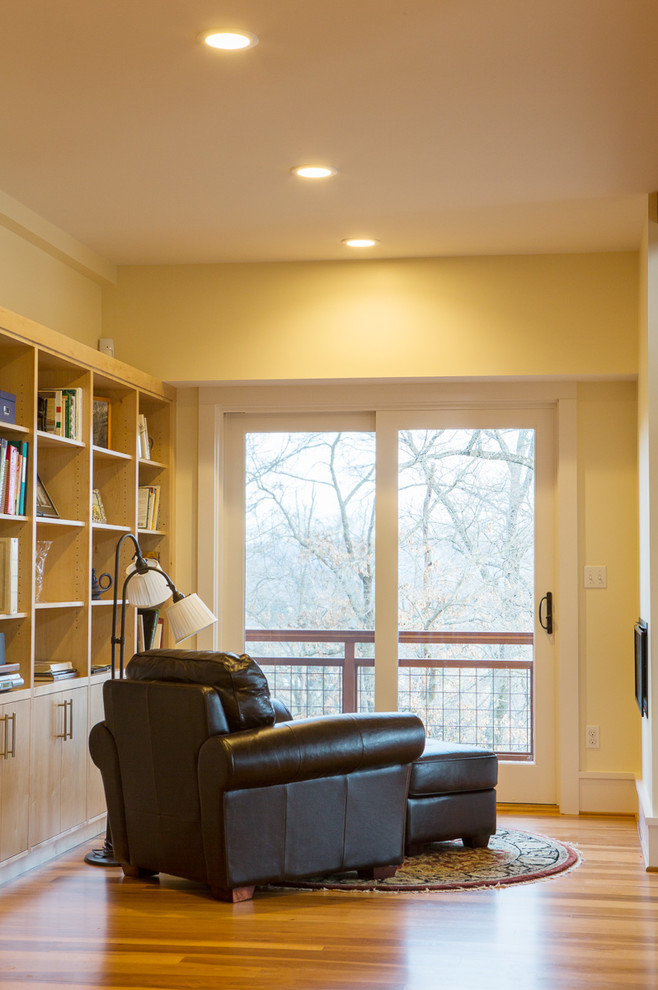 Ejemplo de despacho rústico de tamaño medio sin chimenea con biblioteca, paredes amarillas, suelo de madera en tonos medios y suelo multicolor