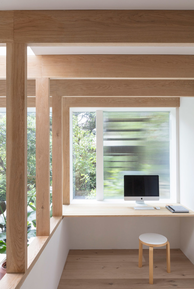 Diseño de despacho escandinavo con paredes blancas, suelo de madera clara, escritorio empotrado y suelo beige
