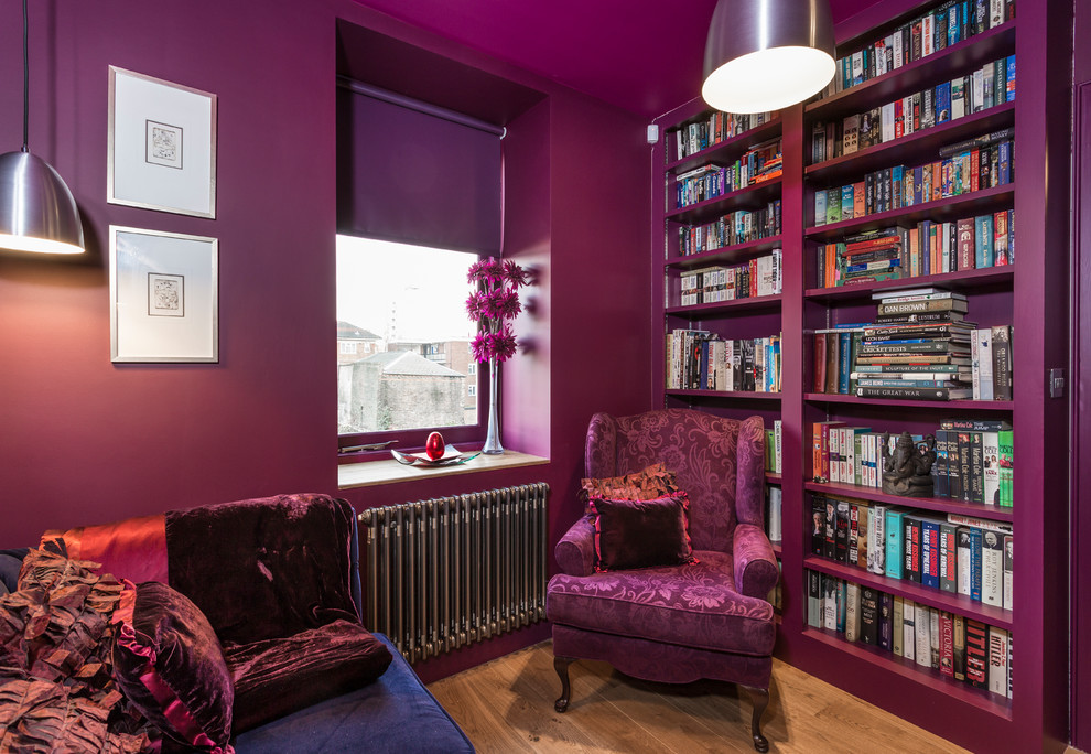 Idéer för ett litet eklektiskt hemmabibliotek, med mellanmörkt trägolv och rosa väggar