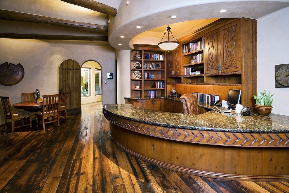 フェニックスにある巨大なサンタフェスタイルのおしゃれな書斎 (白い壁、濃色無垢フローリング、造り付け机、暖炉なし、茶色い床) の写真