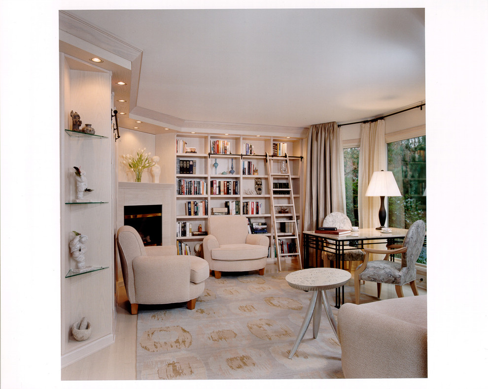 Imagen de despacho clásico grande con biblioteca, paredes beige, suelo de madera clara, chimenea de esquina, marco de chimenea de piedra y escritorio independiente