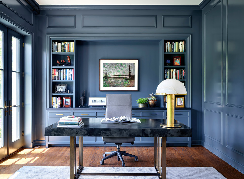 Inspiration för ett vintage hemmabibliotek, med blå väggar, mörkt trägolv, ett fristående skrivbord och brunt golv