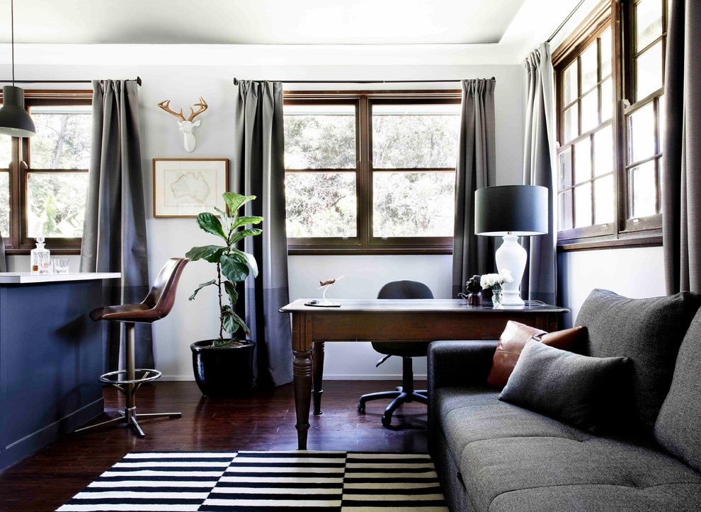 Mittelgroßes Stilmix Arbeitszimmer mit Arbeitsplatz, grauer Wandfarbe, freistehendem Schreibtisch, braunem Boden und dunklem Holzboden in Sydney