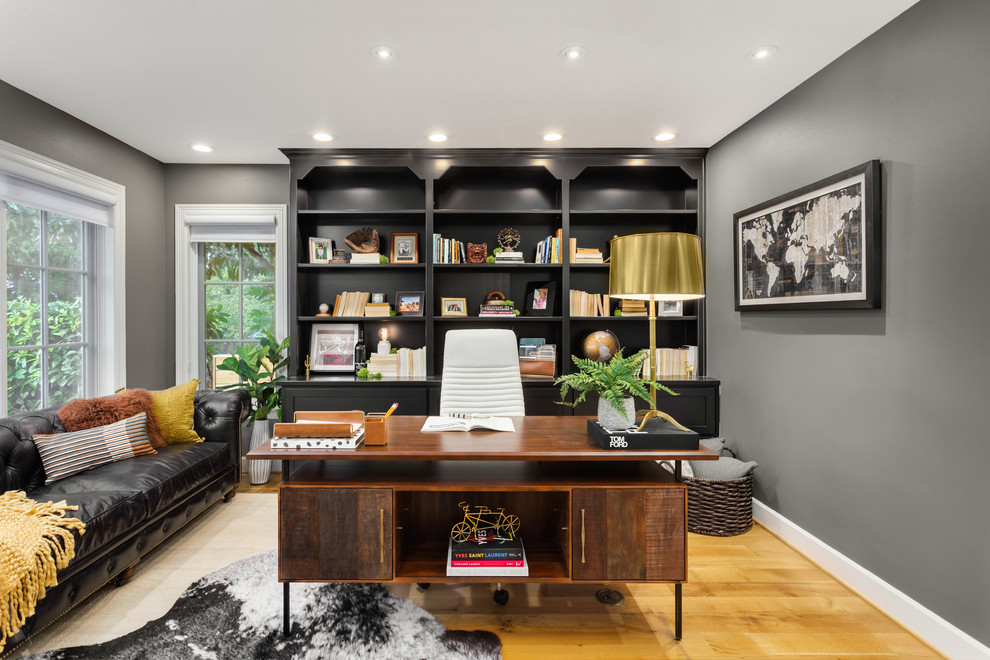 Cette photo montre un bureau chic avec un mur gris, un sol en bois brun, un bureau indépendant et un sol marron.