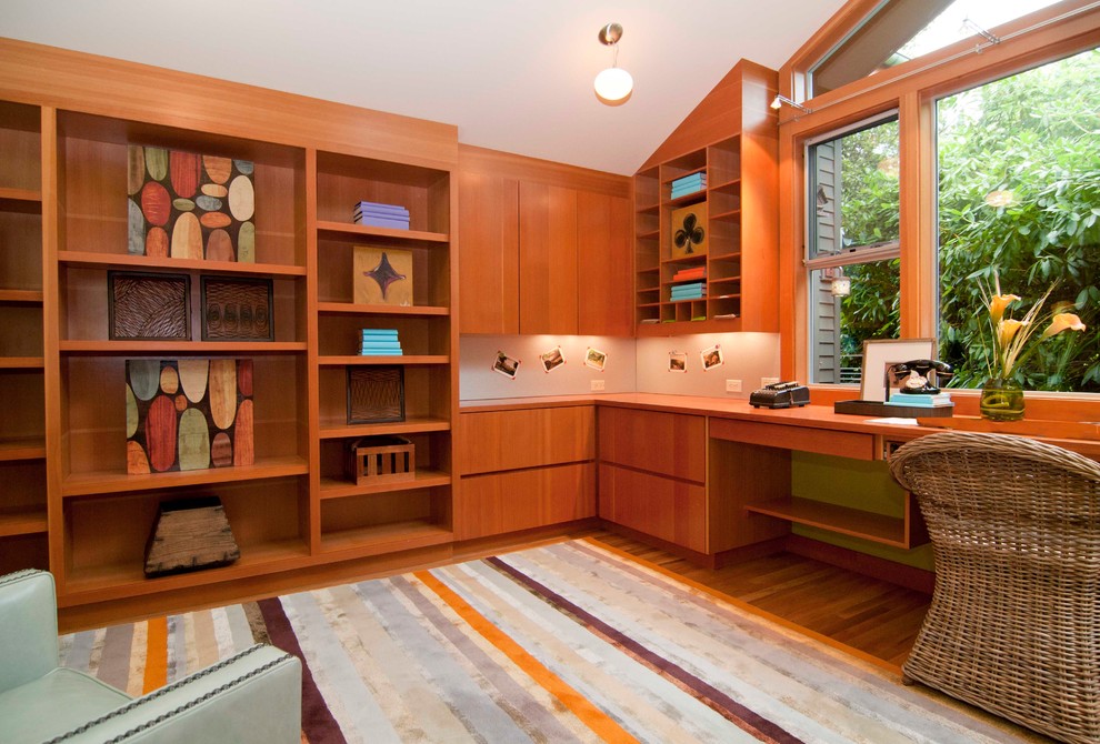 Modern inredning av ett arbetsrum, med mellanmörkt trägolv och ett inbyggt skrivbord