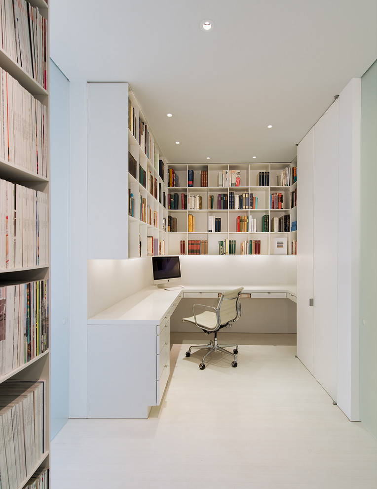 This is an example of a modern home office in DC Metro with white walls and a built-in desk.