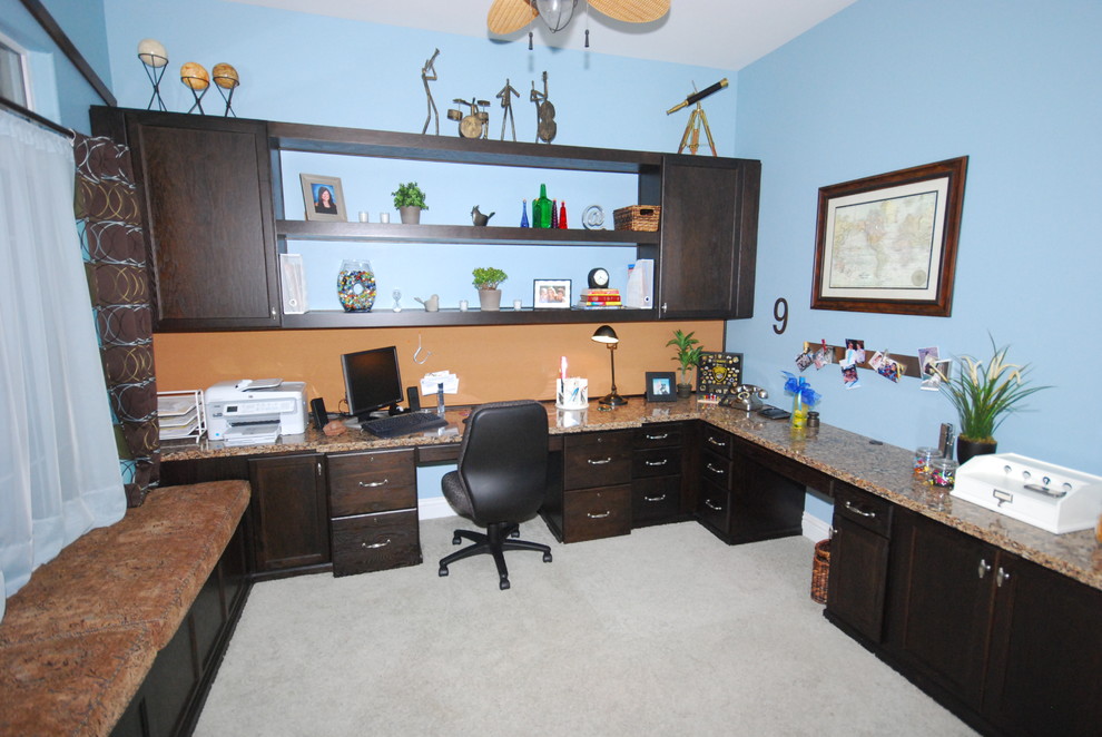 This is an example of a medium sized traditional home office in Other with blue walls, carpet and a built-in desk.