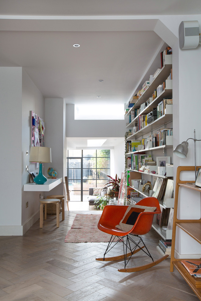 Großes Modernes Arbeitszimmer mit weißer Wandfarbe, braunem Holzboden und Einbau-Schreibtisch in London