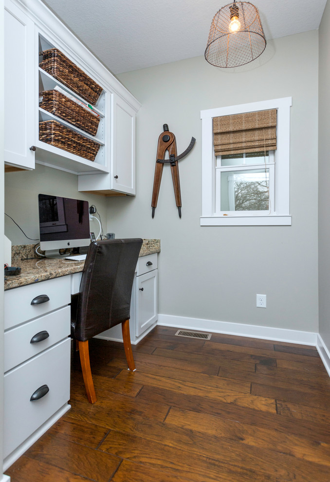 Cette photo montre un petit bureau craftsman avec un mur gris, un sol en bois brun et un bureau intégré.