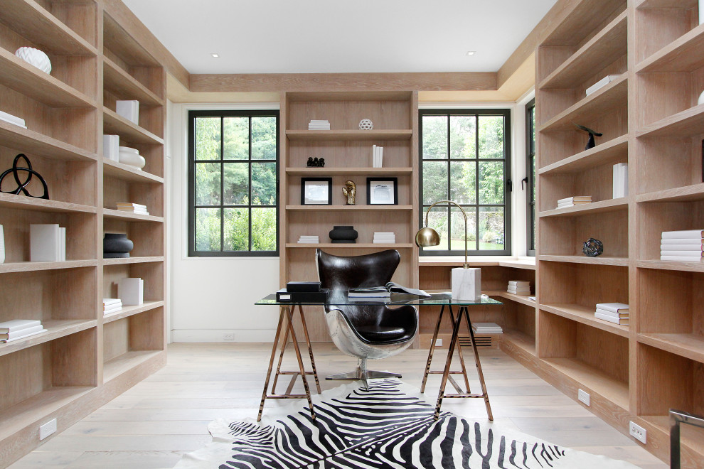 Photo of a large contemporary home office in New York with beige walls, light hardwood flooring, a freestanding desk and beige floors.