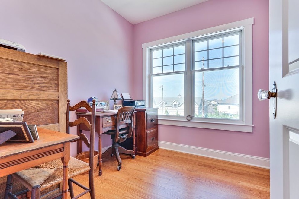 На фото: кабинет среднего размера в стиле кантри с розовыми стенами, паркетным полом среднего тона и отдельно стоящим рабочим столом с