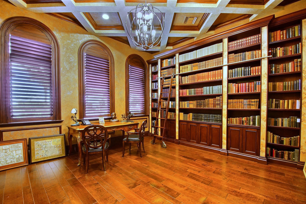 Large elegant freestanding desk dark wood floor home office library photo in Miami with beige walls and no fireplace