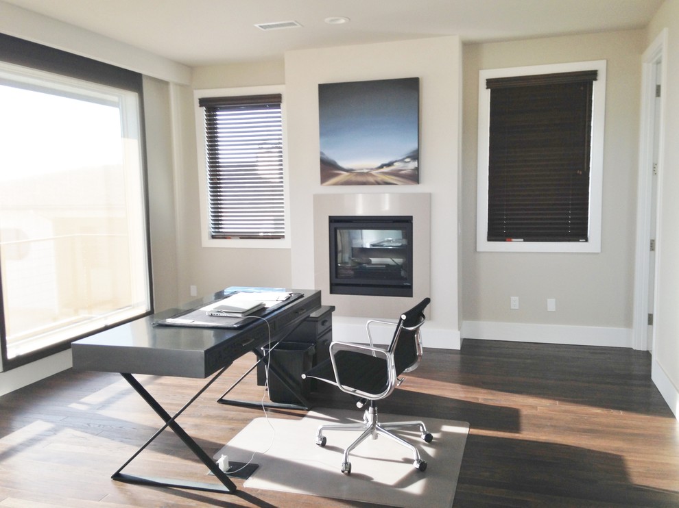 Photo of a large contemporary home office in San Diego with grey walls, medium hardwood flooring, a standard fireplace and a freestanding desk.