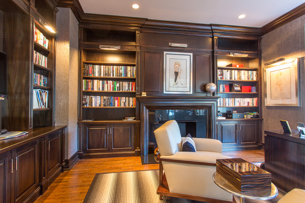 Mittelgroßes Klassisches Arbeitszimmer mit brauner Wandfarbe, dunklem Holzboden, Kamin, gefliester Kaminumrandung, freistehendem Schreibtisch und braunem Boden in New York