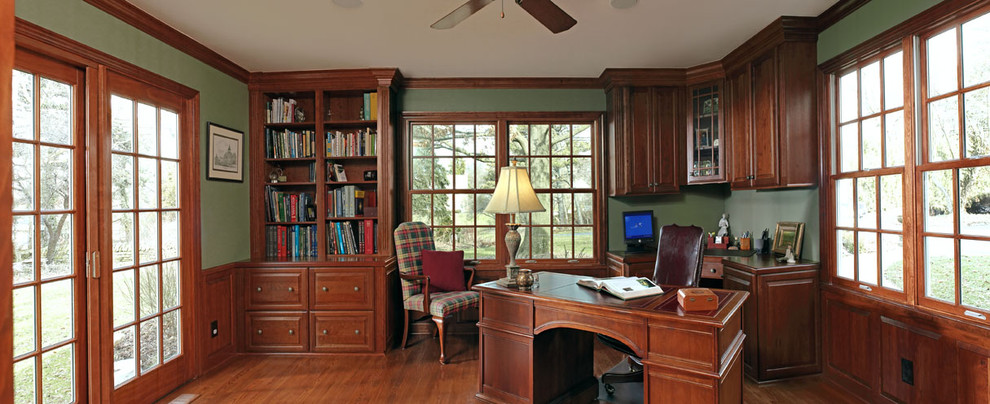 Exempel på ett klassiskt arbetsrum, med gröna väggar, mellanmörkt trägolv och ett fristående skrivbord